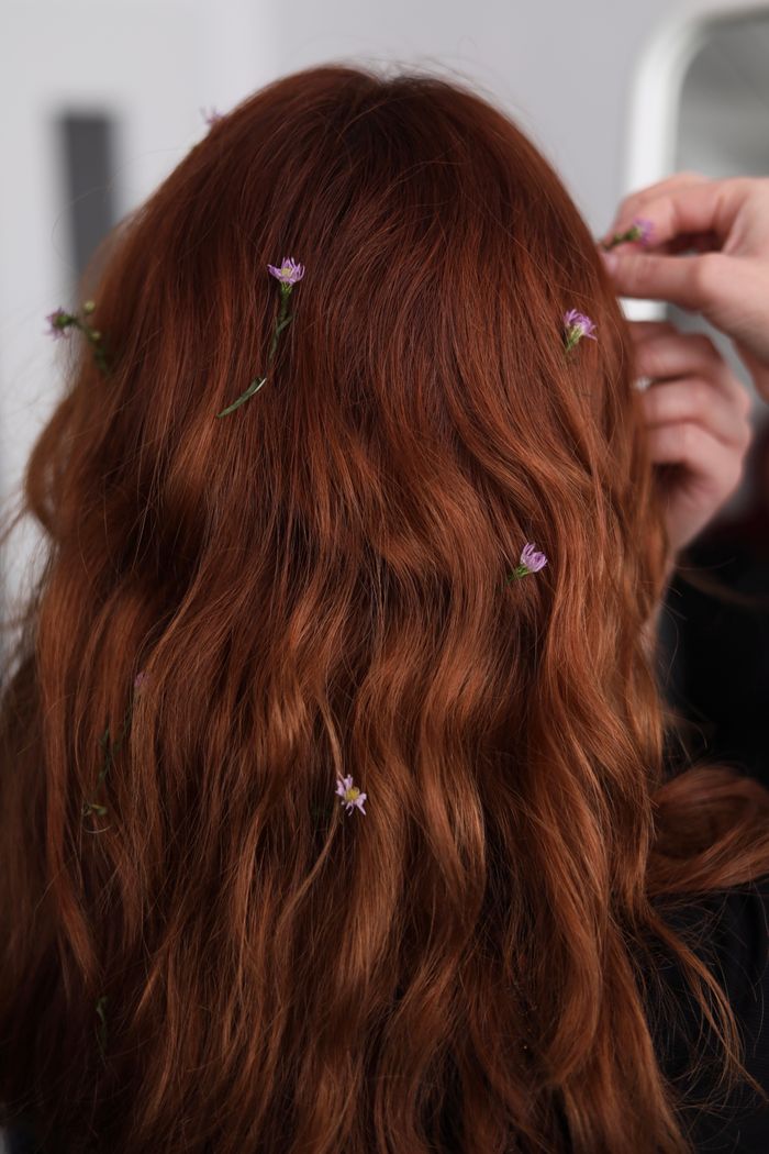 Close-up of a redhead woman with flowers in her hair, showcasing natural beauty.